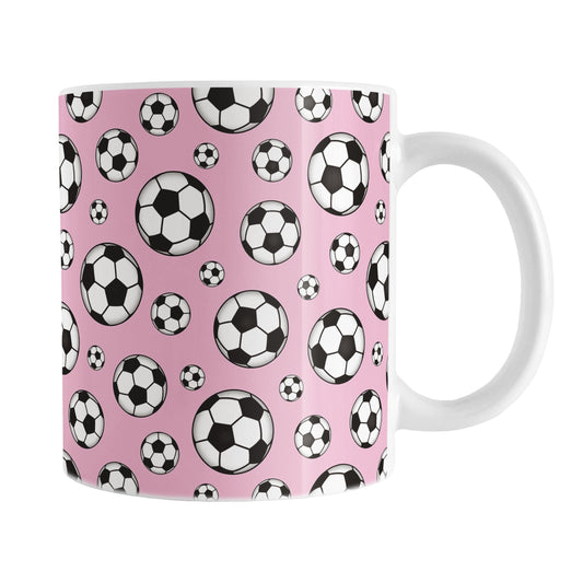 11oz white ceramic mug with a design of soccer balls over pink