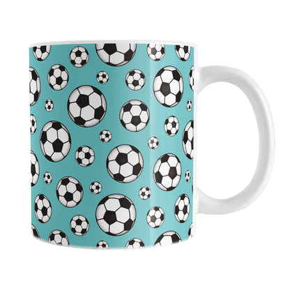 11oz white ceramic mug with a design of soccer balls over teal