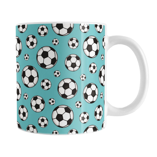 11oz white ceramic mug with a design of soccer balls over teal