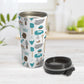 Turquoise Baking Pattern Travel Mug (15oz) at Amy's Coffee Mugs. A stainless steel travel mug designed with a pattern of baking tools like spatulas, whisks, mixers, bowls, and spoons, with cookies, cupcakes, and cake all in a turquoise, gray, brown, and beige color scheme that wraps around the travel mug. Photo shows the travel mug open with the lid laying on the tabletop beside it. 