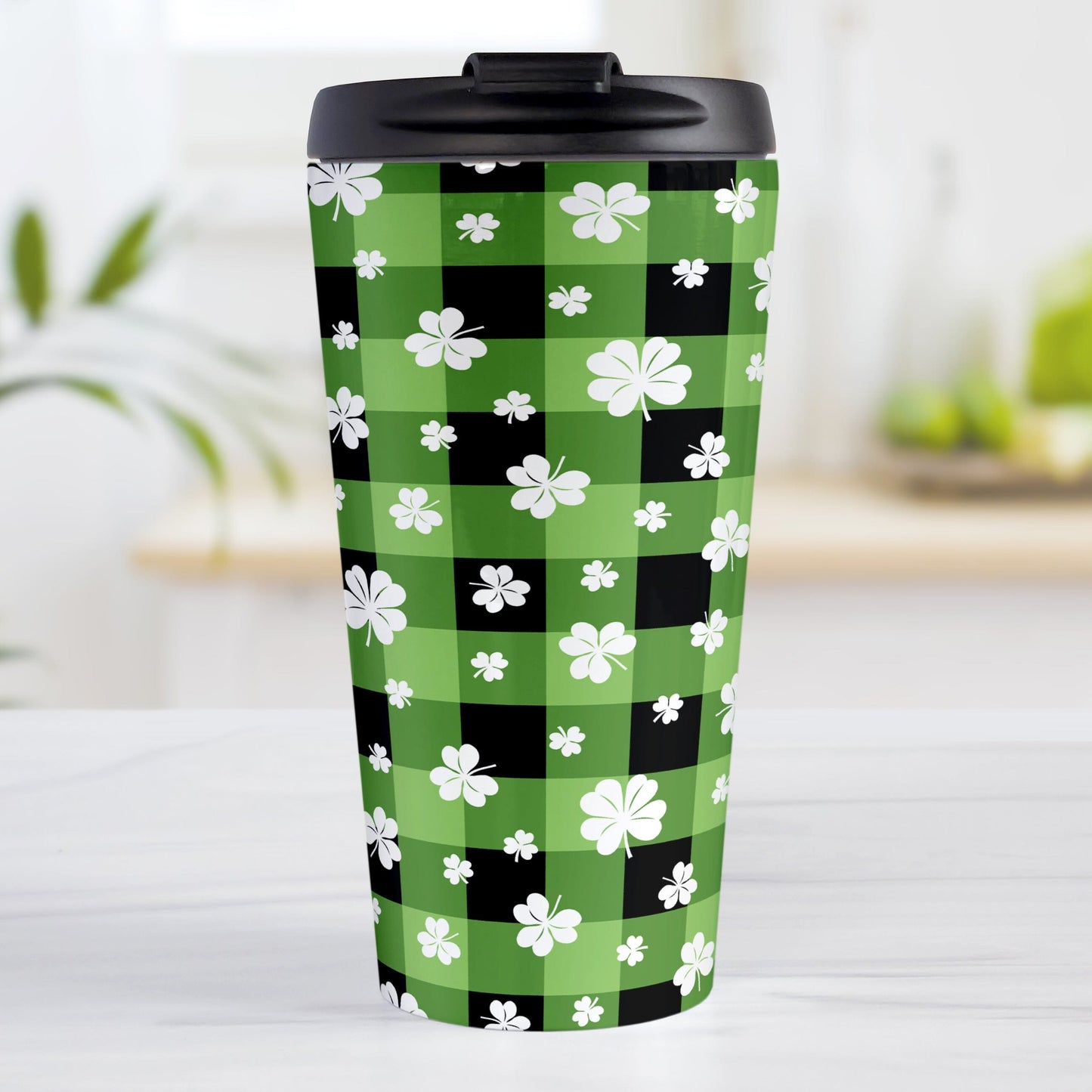 15oz travel mug with green and black checkered (buffalo plaid) pattern and white clovers, on a tabletop