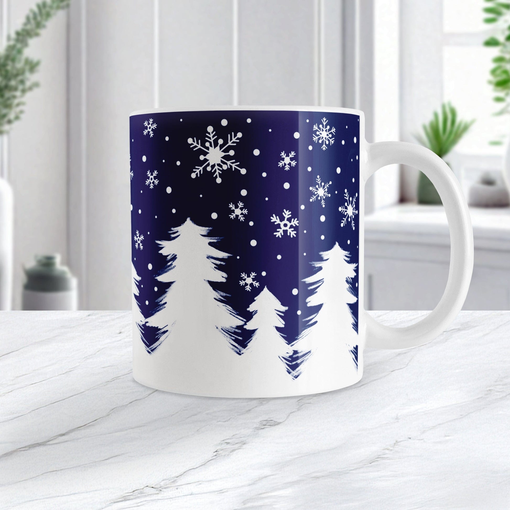 White mug with winter design featuring trees and snowflakes on a blue background, placed on a white surface.