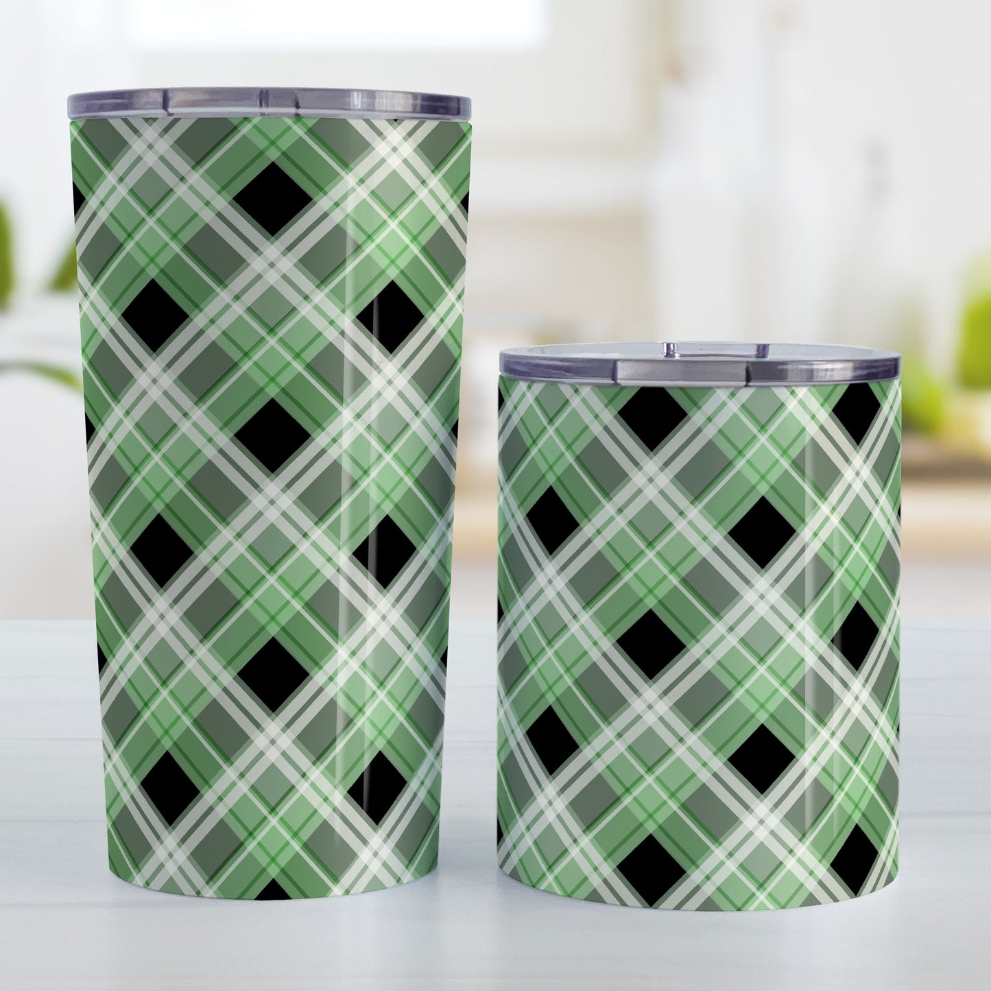 Alternative Black and Green Plaid Tumbler Cup (20oz and 10oz) at Amy's Coffee Mugs. Stainless steel insulated tumbler cups designed with a diagonal green, black, and white plaid pattern that wraps around the cups. Tumbler cups designed for someone who loves plaid patterns and the colors green and black together. Photo shows both sized cups next to each other.