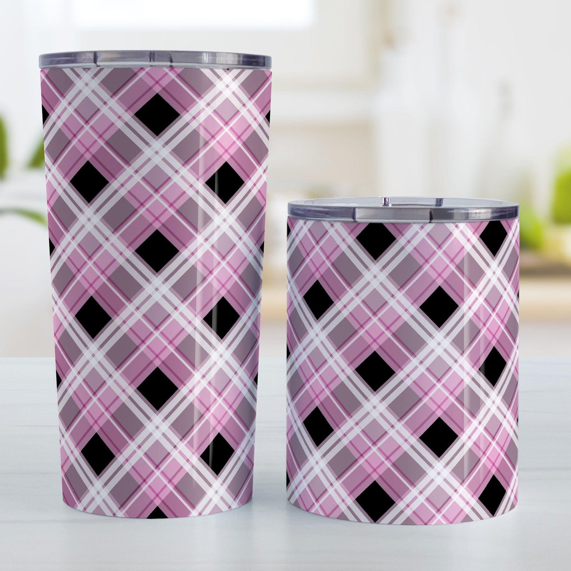 Alternative Black and Pink Plaid Tumbler Cup (20oz and 10oz) at Amy's Coffee Mugs. Stainless steel insulated tumbler cups designed with a diagonal pink, black, and white plaid pattern that wraps around the cups. Tumbler cups designed for someone who loves plaid patterns and the colors pink and black together. Photo shows both sized cups next to each other.