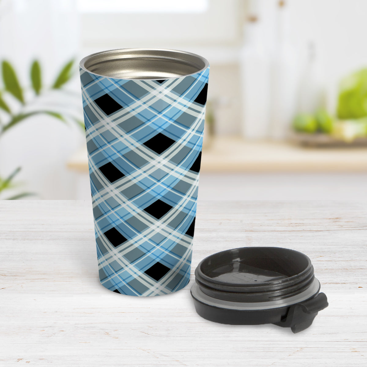 Alternative Blue Plaid Travel Mug (15oz) at Amy's Coffee Mugs. A stainless steel travel mug designed with a diagonal blue, black, and white plaid pattern that wraps around the mug. Designed for someone who likes plaid patterns and loves the color blue. Photo shows the mug open with the lid on the table beside it. 