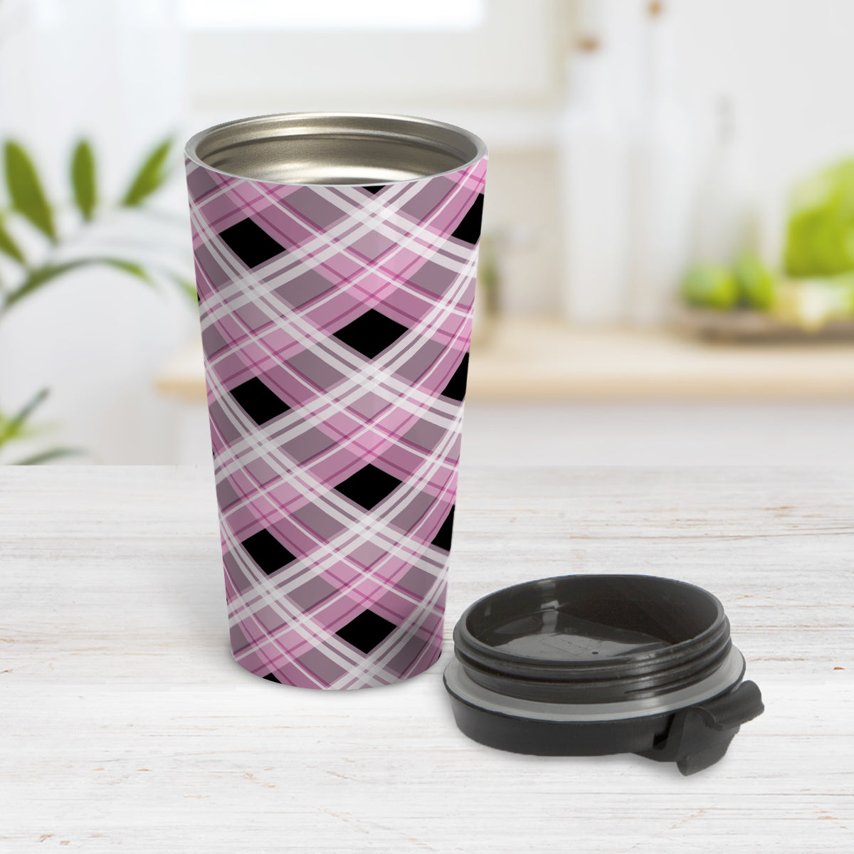 Alternative Pink Plaid Travel Mug (15oz) at Amy's Coffee Mugs. A stainless steel travel mug designed with a diagonal pink, black, and white plaid pattern that wraps around the mug. Designed for someone who likes plaid patterns and loves the color pink. Photo shows the mug open with the lid on the table beside it.