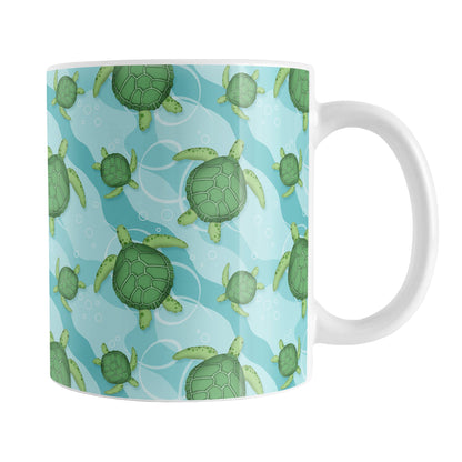 Aquatic Sea Turtle Pattern Mug (11oz) at Amy's Coffee Mugs. A ceramic coffee mug with an aquatic pattern of green sea turtles, swimming over a wavy underwater pattern design in blue and turquoise, that wraps around the mug to the handle.
