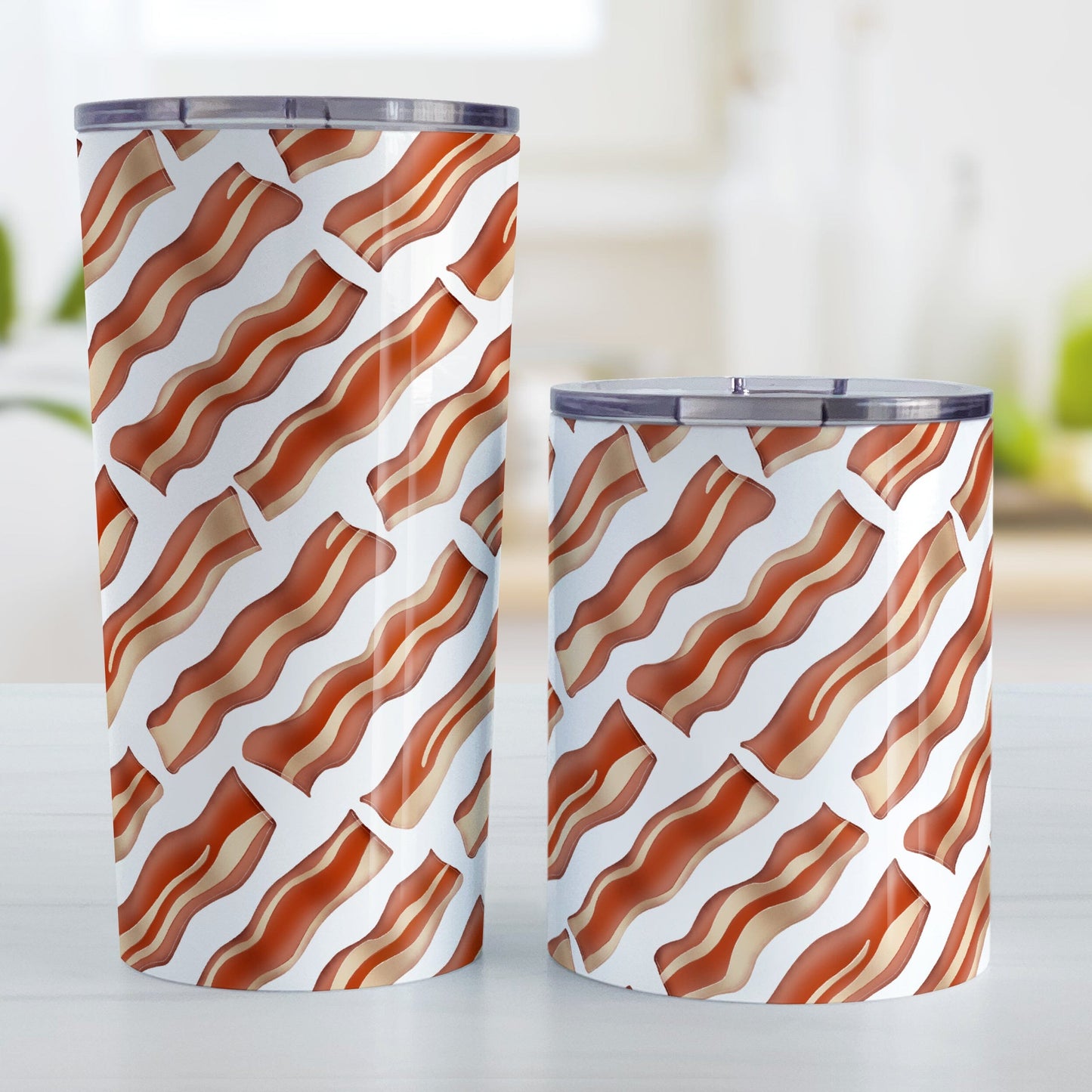 Bacon Pattern Tumbler Cup (20oz or 10oz) at Amy's Coffee Mugs. Stainless steel tumbler cups designed with a diagonal pattern of bacon strips that wraps around the cups. They're perfect for anyone who loves bacon and wants a breakfast-themed cup with their morning meal or while they're at work. Photo shows both sized cups on a table next to each other.