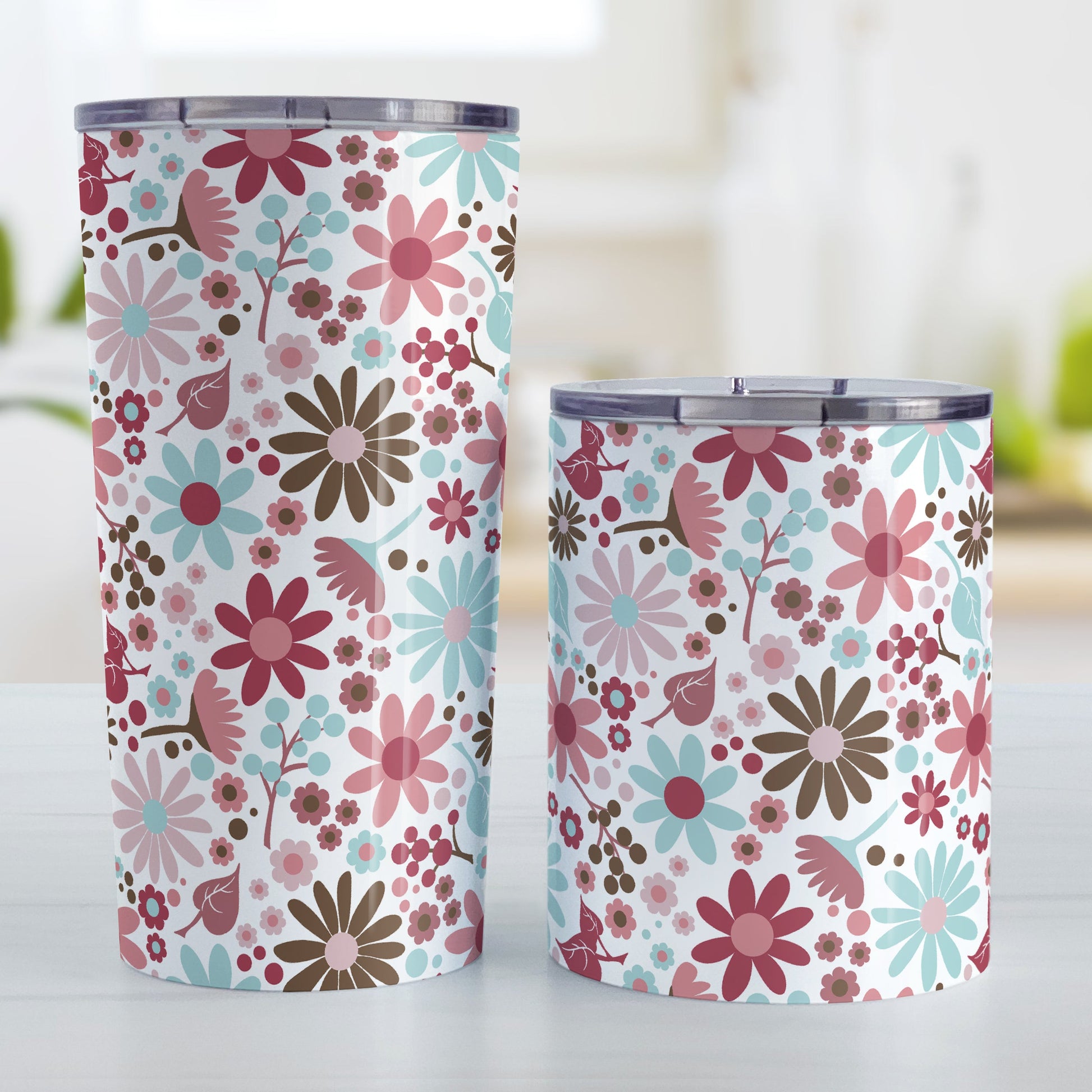 Berry Summer Flowers Tumbler Cup (20oz and 10oz, stainless steel insulated) at Amy's Coffee Mugs. Tumbler cups designed with a lovely summer flowers pattern in beautiful berry pink hues, accented with aqua blue and brown, that wraps around the cups. Photo shows both sized cups on a table next to each other.