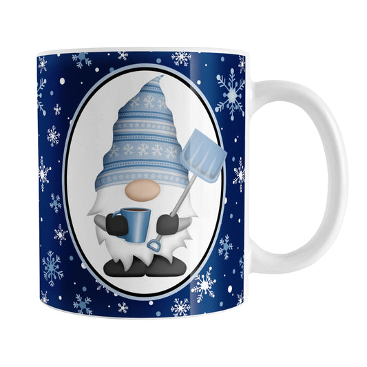 Blue Gnome Snowflakes Mug (11oz) at Amy's Coffee Mugs. A ceramic coffee mug designed with an adorable gnome wearing a festive blue winter hat and holding a hot beverage and a snow shovel in a white oval over a blue night snowflakes background that wraps around the mug to the handle.