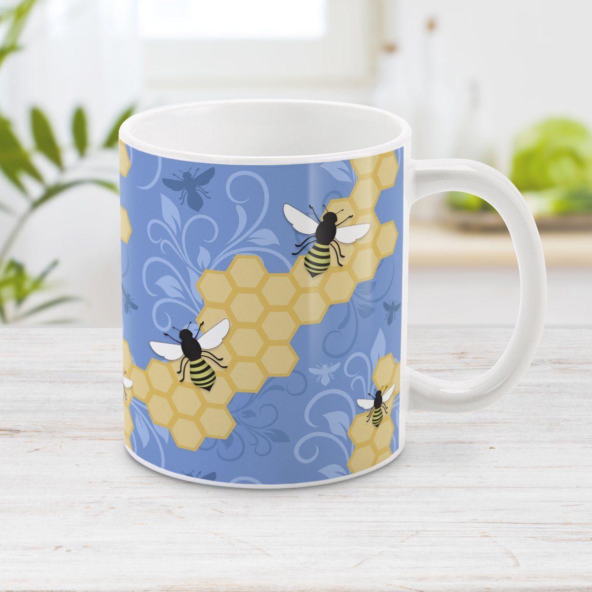 Blue Honeycomb Bee Mug at Amy's Coffee Mugs. A ceramic coffee mug designed with a pattern of black and yellow bees on honeycomb lines over a blue flourish background that wraps around the mug to the handle.