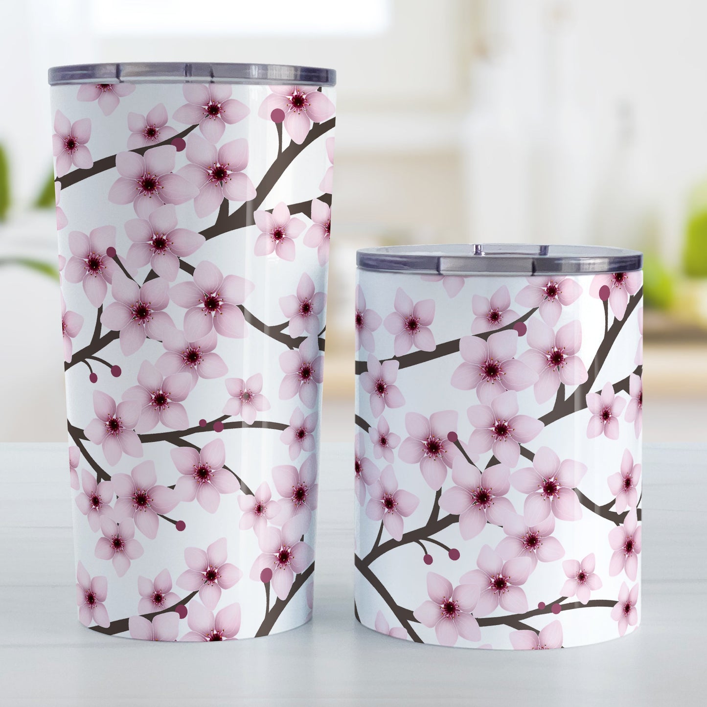 Cherry Blossom Tumbler Cup (20oz and 10oz) at Amy's Coffee Mugs. Stainless steel insulated tumbler cups designed with a pattern of pink cherry blossom flowers on branches that wraps around the cups. Photo shows both sized cups next to each other.