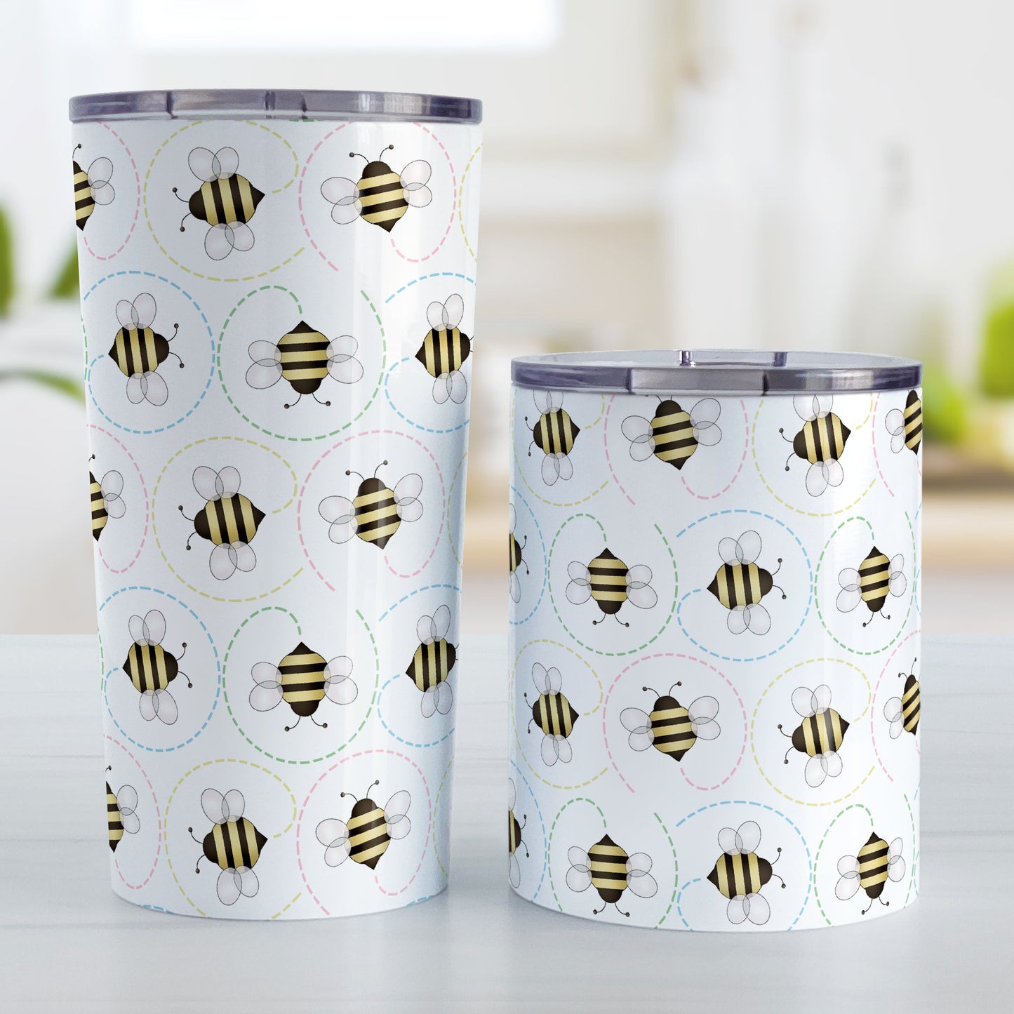 Circling Dainty Bee Pattern Tumbler Cup (20oz and 10oz, stainless steel insulated) at Amy's Coffee Mugs. Bee tumbler cups with adorable dainty black and yellow bees in a pattern around the cups with colorful dotted line circling flight paths. A minimalist bee design for bee lovers who also love color and happy designs. The different sized cups are displayed next to each other.