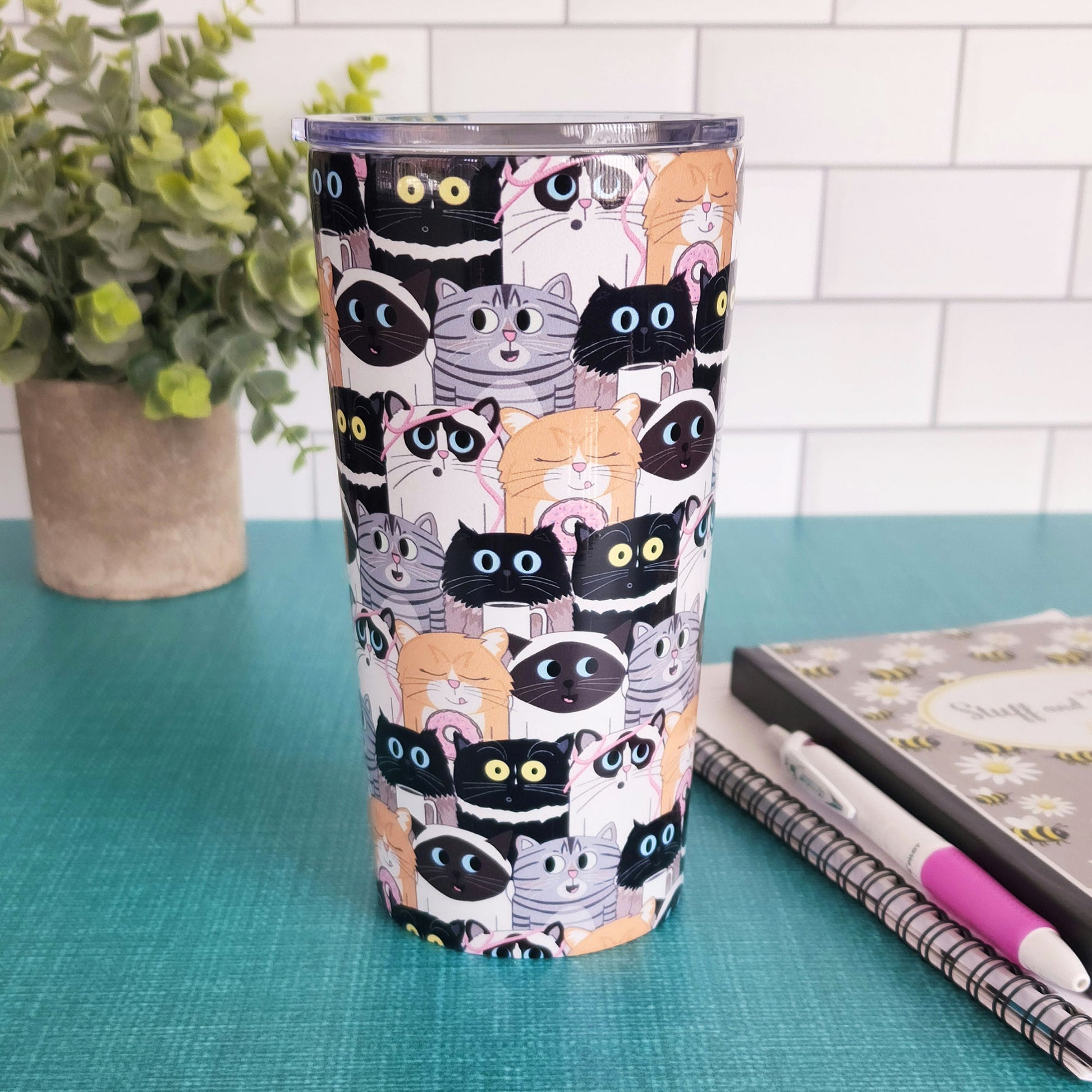 Cute Cat Stack Pattern Tumbler Cup (20oz) at Amy's Coffee Mugs. A cute cats tumbler cup with an illustrated pattern of different breeds of cats with different fun expressions, with yarn, coffee, and donuts. This stacked pattern of cats wraps around the cup. Picture shows both cup sizes on a counter next to each other.