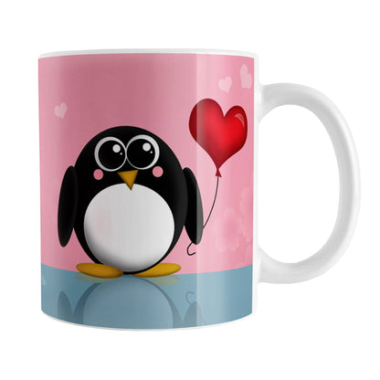 Cute Penguin Heart Balloon Mug (11oz) at Amy's Coffee Mugs. A ceramic coffee mug designed with an adorable rounded penguin holding a red heart balloon on both sides of the mug over a pink and blue background that wraps around the mug up to the handle.