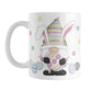Easter Eggs Bunny Gnome Mug (11oz) at Amy's Coffee Mugs. A ceramic coffee mug designed with an adorable gnome with bunny ears and holding a large Easter egg. Colorful little Easter eggs lay on the ground beside him with little flowers floating around.