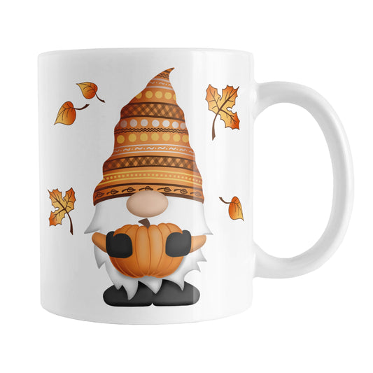 Fall Pumpkin Gnome Mug (11oz) at Amy's Coffee Mugs. A ceramic coffee mug designed with a fall themed gnome holding an orange pumpkin with an orange festive hat, and leaves in the air around it, on both sides of the mug.