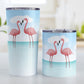 Flamingos in the Water Tumbler Cups (20oz or 10oz) at Amy's Coffee Mugs. Stainless steel tumbler cups designed with an illustration of two pink flamingos standing in the ocean water, with fresh and clean open water with ripples and a bright blue sky. Photo shows both sized cups on a table next to each other. 