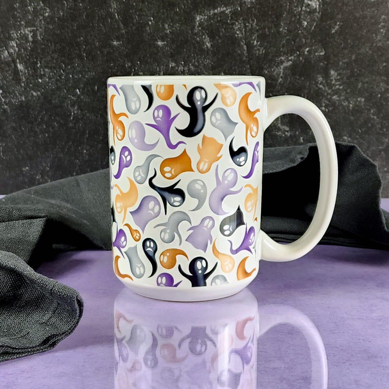 Ghosts and Spirits Halloween Mug (15oz) on a glossy purple table with a slate black background. 