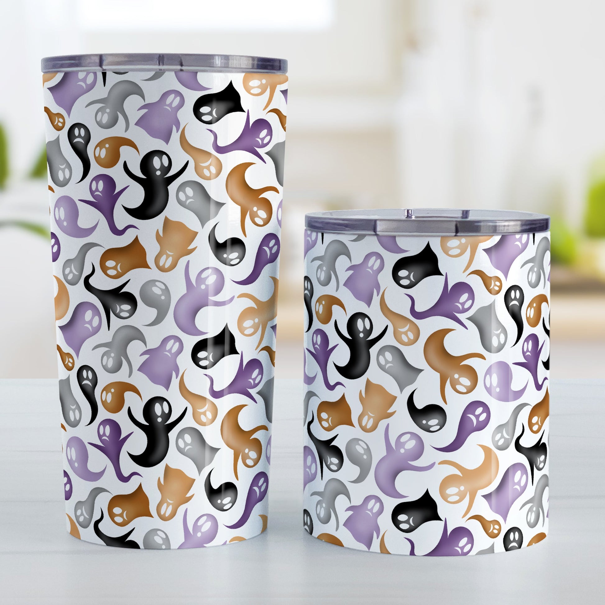 Ghosts and Spirits Halloween Tumbler Cup (20oz and 10oz) at Amy's Coffee Mugs. Stainless steel insulated tumbler cups designed with a whimsical pattern of purple, orange, black and gray ghosts and spirits that wraps around the cups. Photo shows both sized cups next to each other.