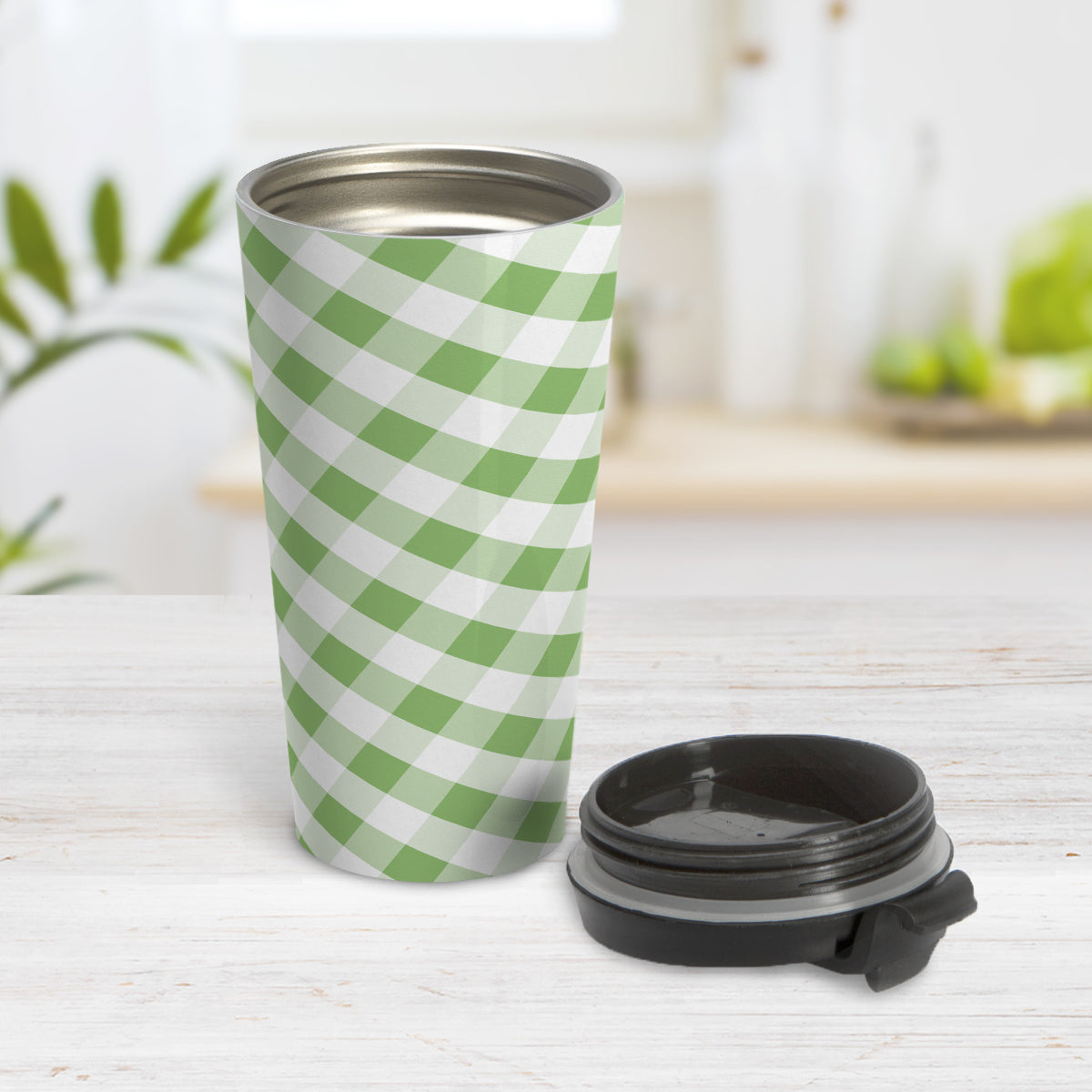 Green Gingham Travel Mug (15oz) at Amy's Coffee Mugs. A travel mug designed with a slanted green and white gingham pattern that wraps around the travel mug. Photo shows the mug open on a table with its lid beside it.
