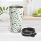 Green Hearts and Paw Prints Travel Mug (15oz) at Amy's Coffee Mugs. A stainless steel travel mug designed with a pattern of hearts and paw prints in brown and different shades of green that wraps around the mug. This travel mug is perfect for people love dogs and cute paw print designs. Photo shows the mug with the lid off, on the table next to the cup.