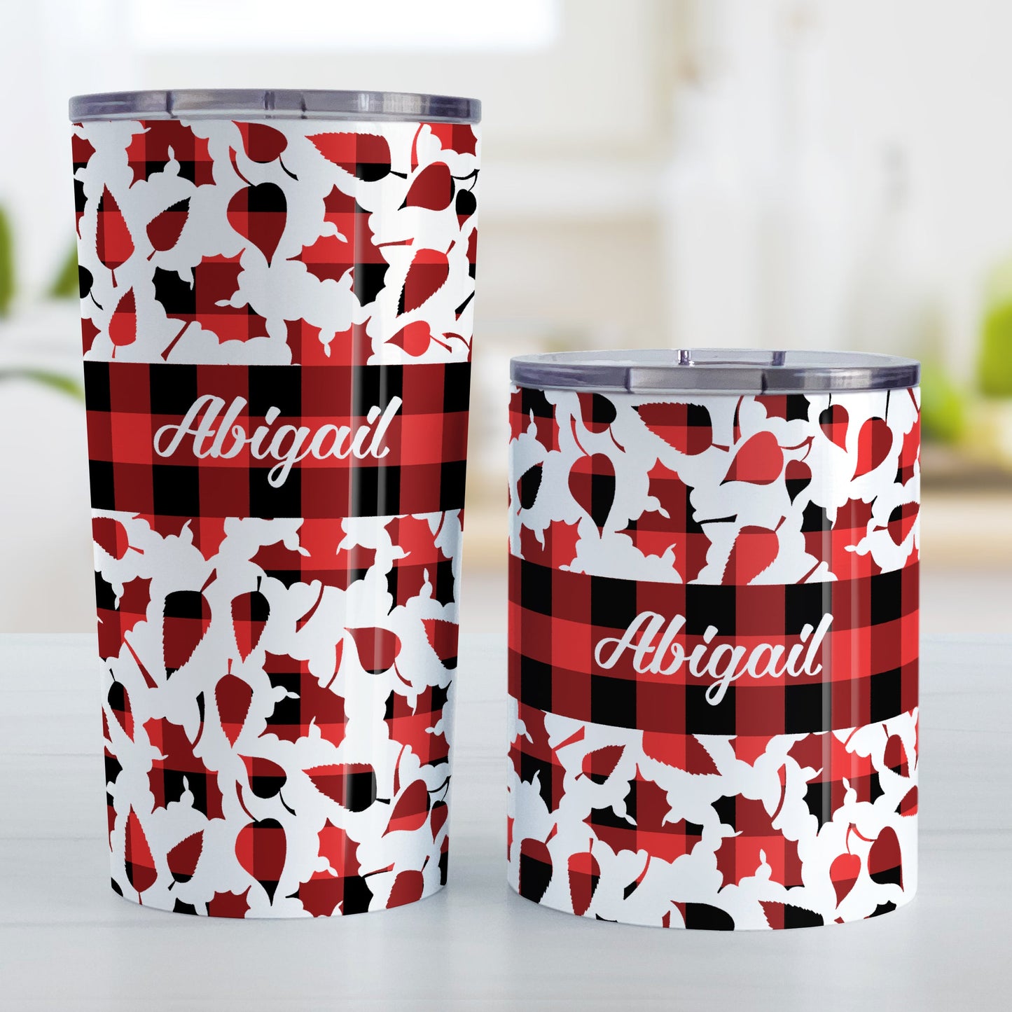 Personalized Buffalo Plaid Leaves Fall Tumbler Cup (20oz or 10oz) at Amy's Coffee Mugs. Stainless steel insulated tumbler cups designed with a pattern of leaves with a red and black buffalo plaid pattern that wraps around the cups. There is a buffalo plaid stripe over middle area of the leaves with your name custom printed in a white script font.
