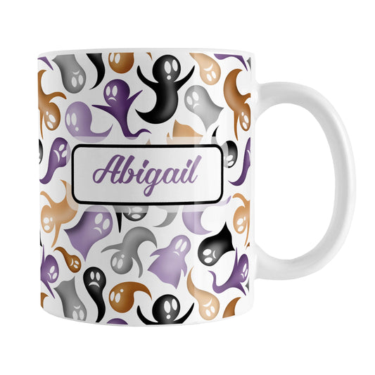 Personalized Ghosts and Spirits Halloween Mug (11oz) at Amy's Coffee Mugs. A ceramic coffee mug designed with a whimsical pattern of purple, orange, black and gray ghosts and spirits that wraps around the mug to the handle. Your personalized name is custom printed in a purple script font on both sides of the mug over the Halloween pattern.