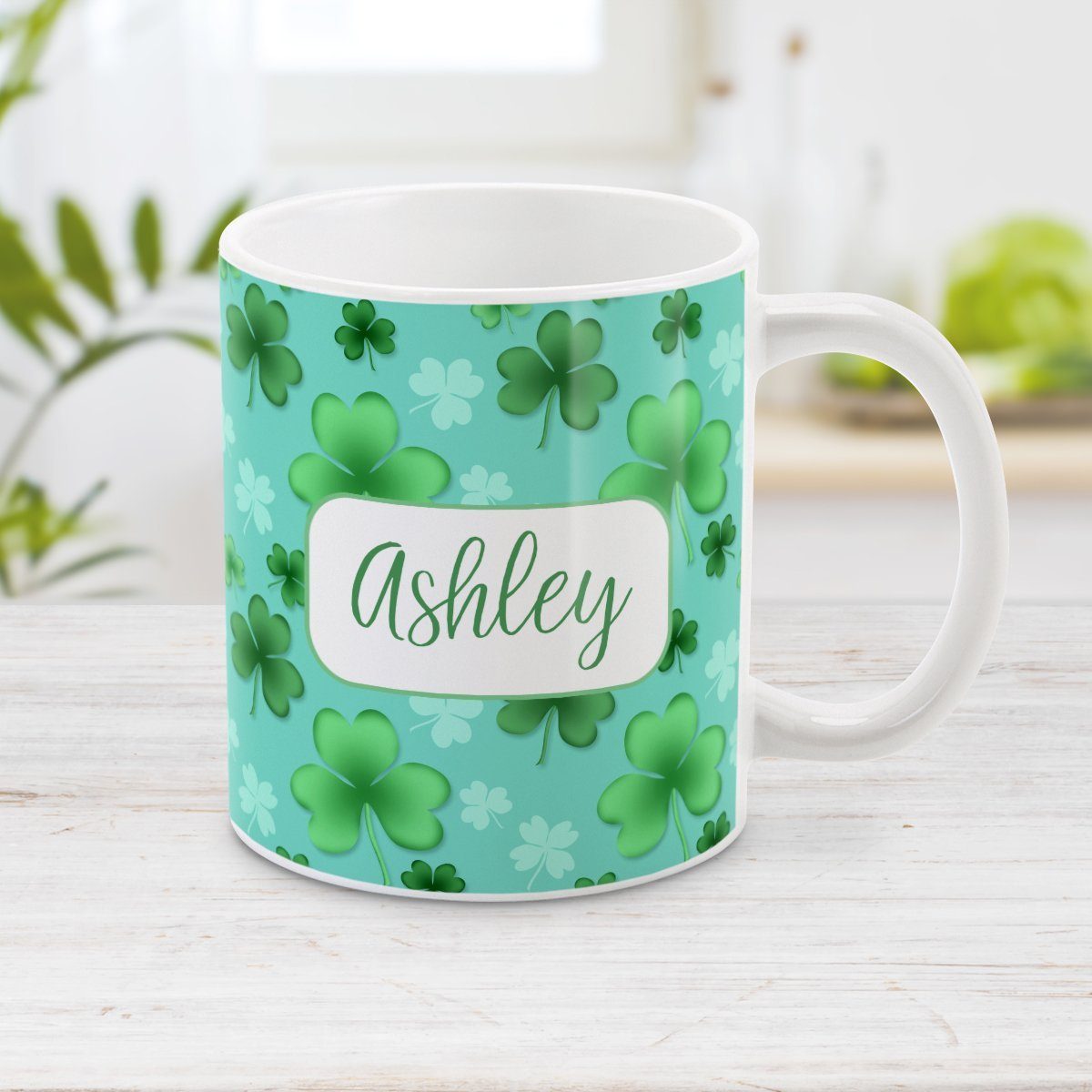 Personalized Lucky Clover Pattern Teal and Green Mug at Amy's Coffee Mugs. A ceramic coffee mug designed with a lucky green clover pattern with a 4-leaf clover among 3-leaf clovers, in different shades of green, over a teal background that wraps around the mug to the handle. Your name is personalized in green on white, over the lucky clover pattern.
