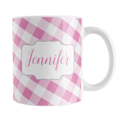 Personalized Pink Gingham Mug (11oz) at Amy's Coffee Mugs. A ceramic coffee mug designed with a slanted pink and white gingham pattern that wraps around the mug up to the handle. Your personalized name is custom-printed in a pink script font on both sides of the mug over the gingham pattern.