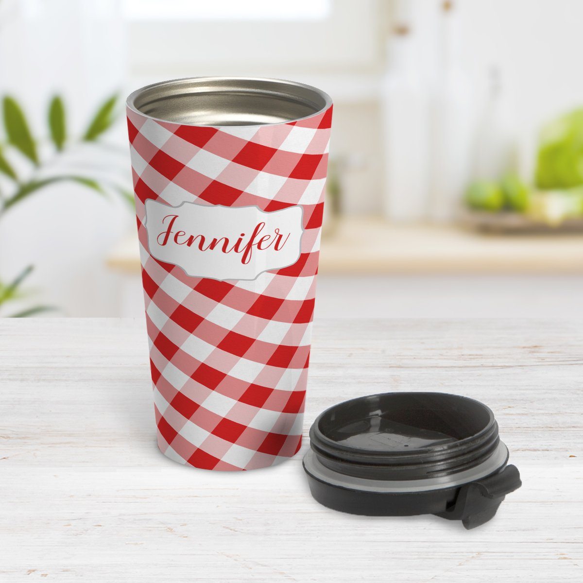 Personalized Red Gingham Travel Mug at Amy's Coffee Mugs. A travel mug designed with a slanted red and white gingham pattern that wraps around the travel mug. Your personalized name is custom-printed in a red script font in a white frame design over the gingham pattern. Photo shows the mug open on a table with its lid beside it.