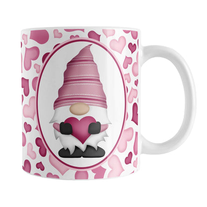 Pink Gnome Hearts Mug (11oz) at Amy's Coffee Mugs. A ceramic coffee mug designed with an adorable pink gnome in a white oval on both sides of the mug over a pattern of cute hearts in different shades of pink that wrap around the mug to the handle.
