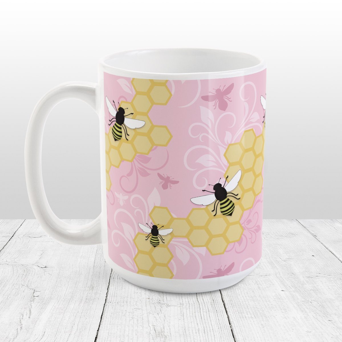 Pink Honeycomb Bee Mug at Amy's Coffee Mugs. A ceramic coffee mug designed with a pattern of black and yellow bees on honeycomb lines over a pink flourish background that wraps around the mug to the handle.