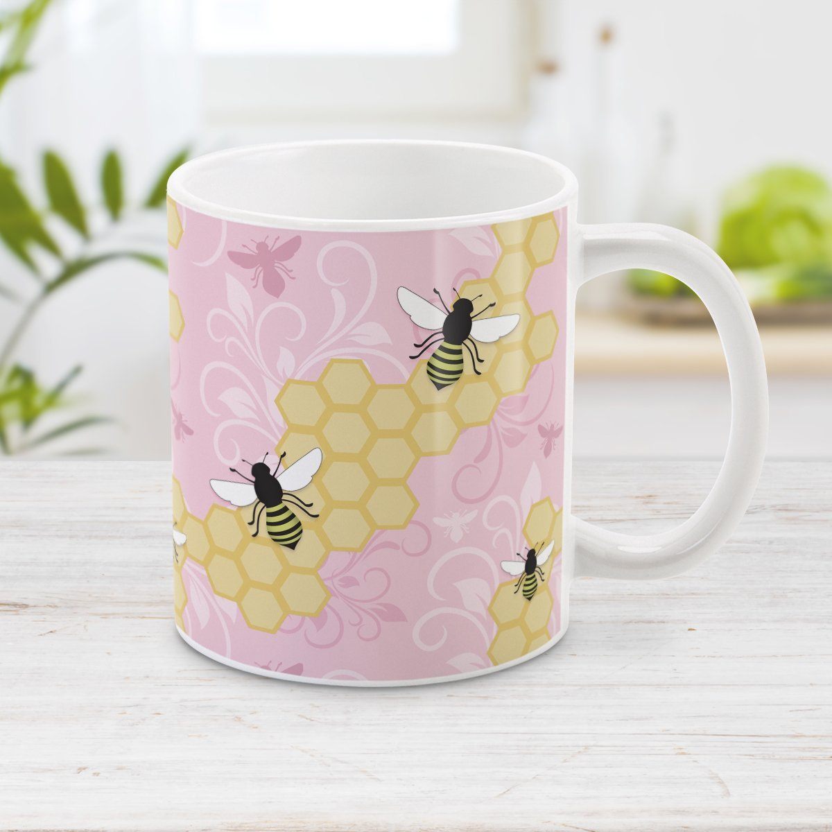 Pink Honeycomb Bee Mug at Amy's Coffee Mugs. A ceramic coffee mug designed with a pattern of black and yellow bees on honeycomb lines over a pink flourish background that wraps around the mug to the handle.