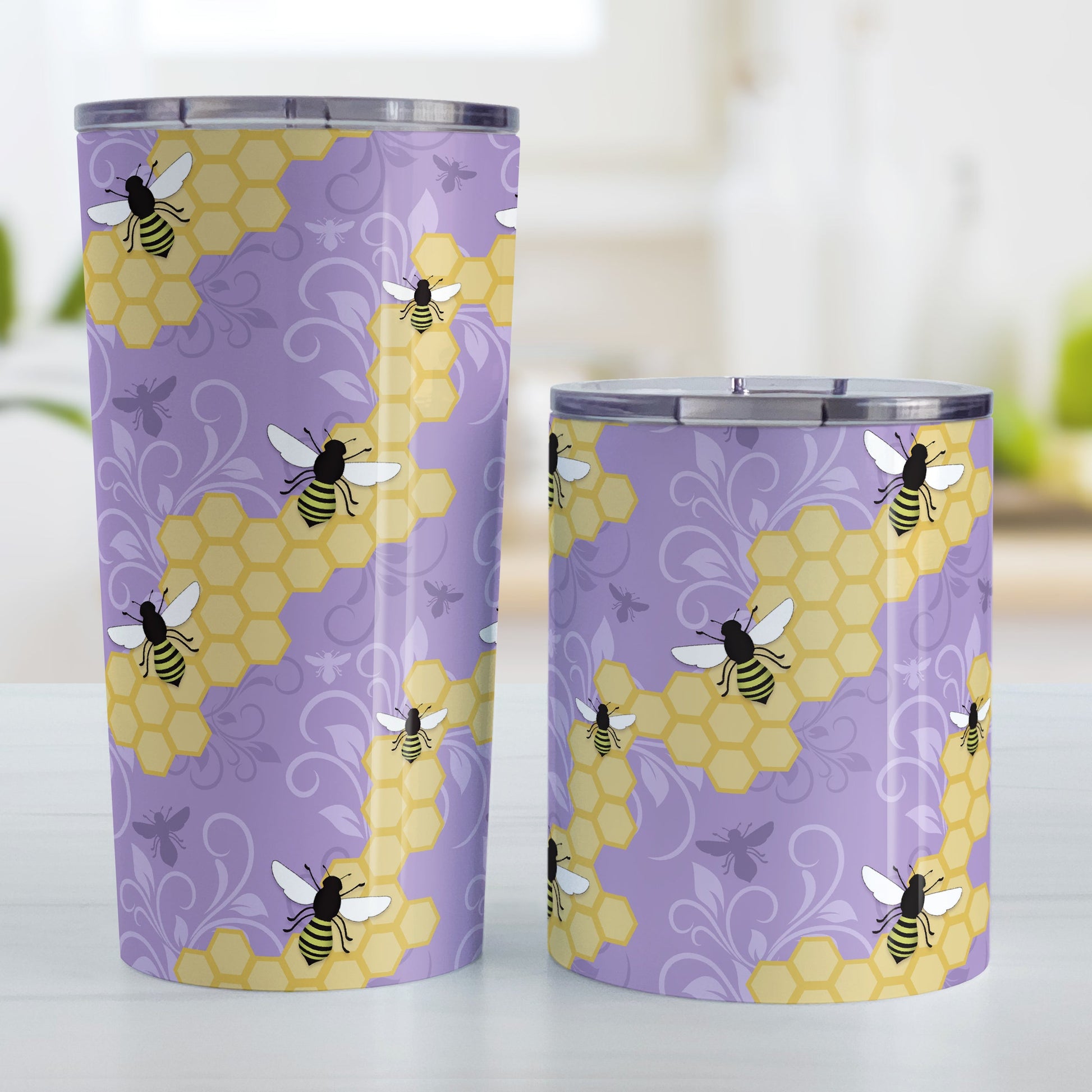 Purple Honeycomb Bee Tumbler Cup (20oz and 10oz, stainless steel insulated) at Amy's Coffee Mugs. Tumbler cups designed with a pattern of black and yellow bees on honeycomb lines over a purple flourish background that wraps around the cups. Photo shows both sized cups next to each other.