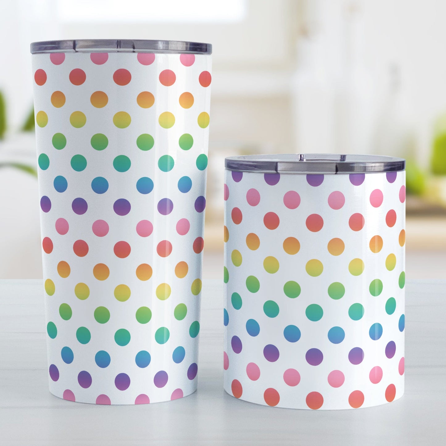 Rainbow Polka Dots Tumbler Cup (20oz or 10oz) at Amy's Coffee Mugs. Stainless steel tumbler cups designed with a colorful pattern of polka dots in a rainbow color progression that wraps around the cups. Photo shows both sized cups next to each other on a table.