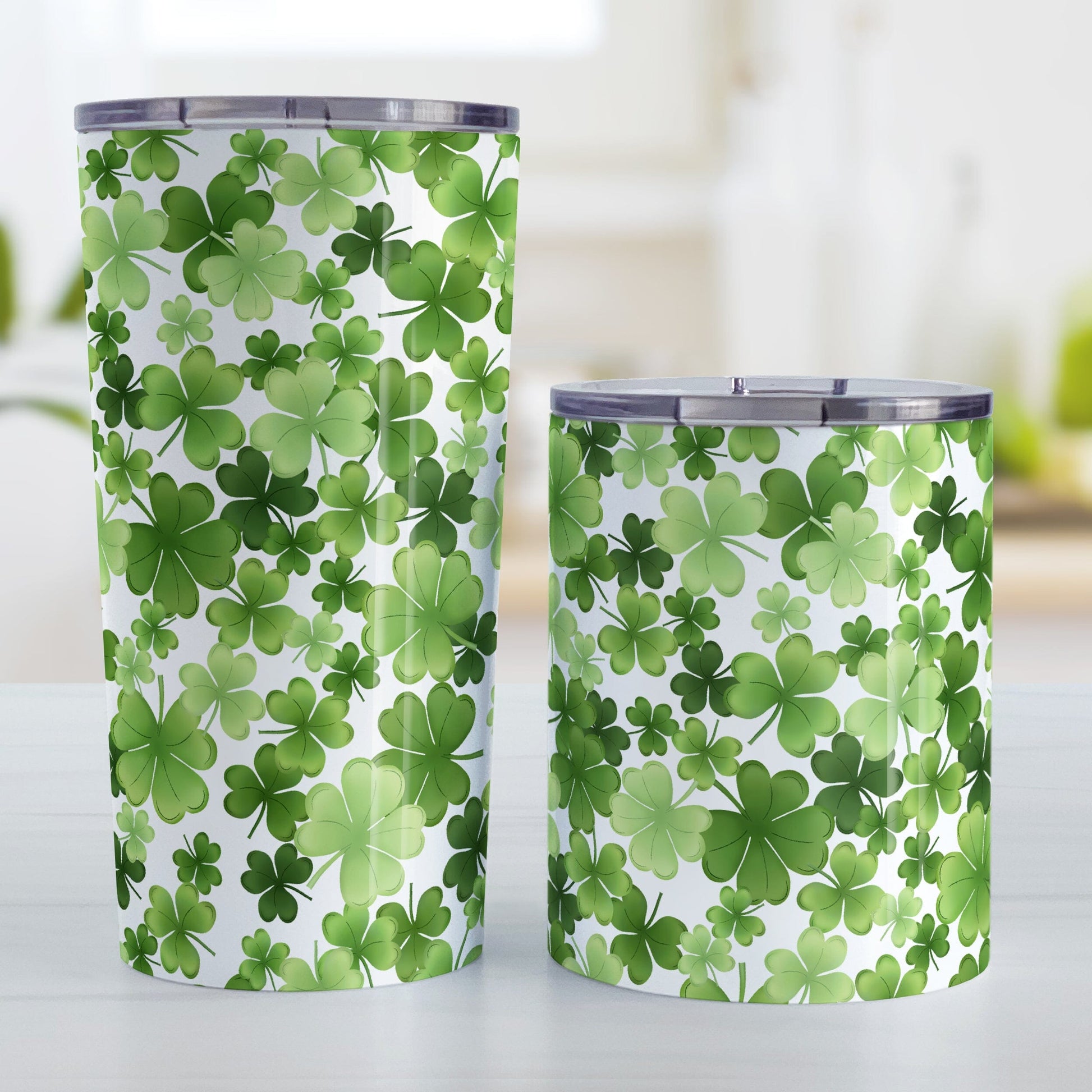 Shamrocks and 4-Leaf Clovers Tumbler Cup (20oz or 10oz) at Amy's Coffee Mugs. Stainless steel insulated tumbler cups designed with an organic-like pattern of green shamrocks and 4-leaf clovers in different shades of green that wraps around the cups. Photo shows both sized cups on a table next to each other.