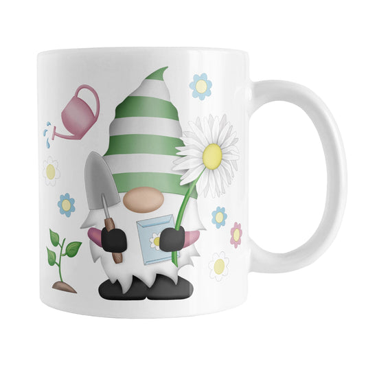 Spring Gardening Gnome Mug (11oz) at Amy's Coffee Mugs. A ceramic coffee mug designed with an adorable gnome in spring colors holding a gardening spade, seeds packet, and an oversized daisy, with a plant, watering can and flowers around him.