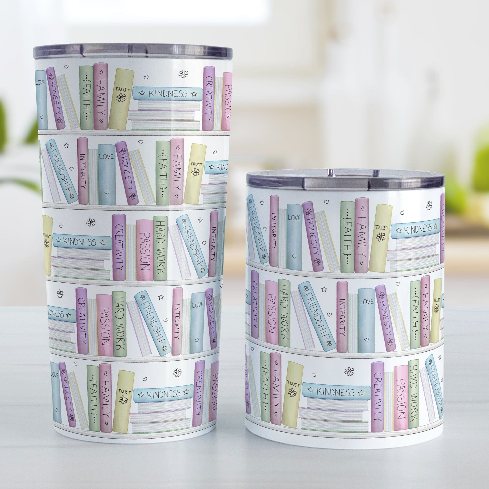 The Building Books of Life - Inspirational Reading Tumbler Cups (20oz or 10oz) at Amy's Coffee Mugs. Stainless steel tumbler cups designed with a colorful pattern of books on a bookshelf each with an inspirational title that all could be considered important building blocks of life, such as love, family, integrity, passion, faith, creativity, and more. Photo shows both sized cups on a table next to each other.