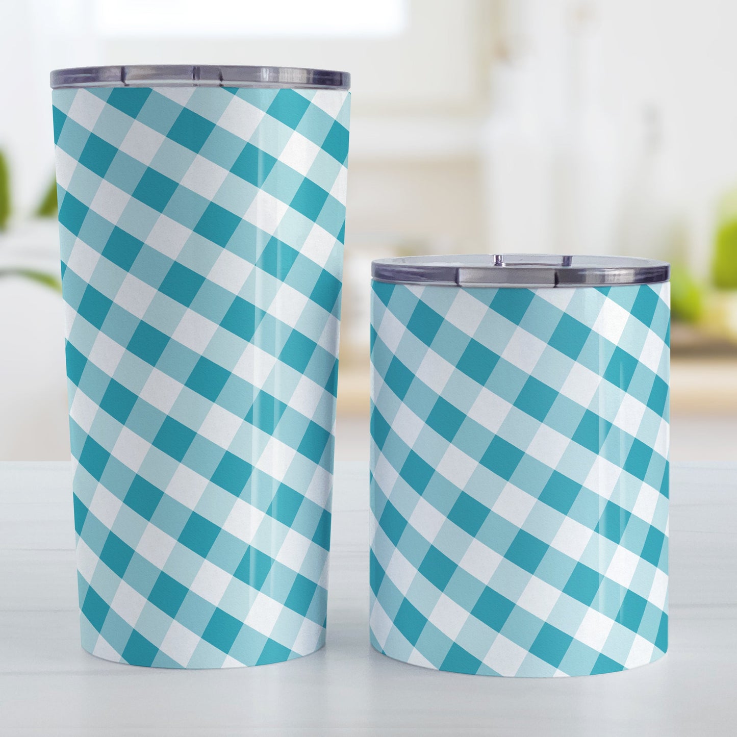 Turquoise Gingham Tumbler Cup (20oz and 10oz, stainless steel insulated) at Amy's Coffee Mugs. A tumbler cup designed with a slanted turquoise and white gingham pattern that wraps around the cup. Photo shows both sized cups on a table next to each other.