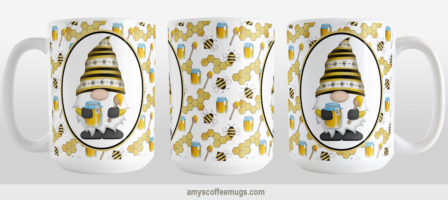 Yellow Gnome Honey Jar Bee Mug (15oz) at Amy's Coffee Mugs. A ceramic coffee mug designed with an adorable gnome wearing a yellow bee-themed hat and holding a honey jar and honey dipper in a white oval over a pattern background that wraps around the mug to the handle with bees, honey jars, honey dippers, and honeycomb. Photo shows three sides of the mug to see the entire printed design.